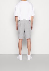 Grå bomullsshorts med resårmidja och sidoficka, kombinerat med en enkel vit t-shirt med kort ärm och vita sneakers.