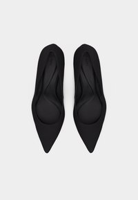 Μαύρα φλατ παπούτσια με μυτερή μύτη και κομψό σχέδιο, απεικονισμένα από πάνω σε λευκό φόντο.