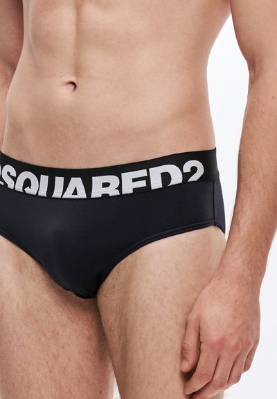 Μαύρα ανδρικά εσώρουχα με αντιθετική μέση σε μαύρο και λευκό, όπου αναγράφεται "DSQUARED2." Με ομαλή υφή και εφαρμογή που αγκαλιάζει το σώμα.