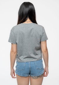 Gray short-sleeve t-shirt with a relaxed fit, made from soft fabric. Paired with blue denim shorts, featuring rolled hems and back pockets.