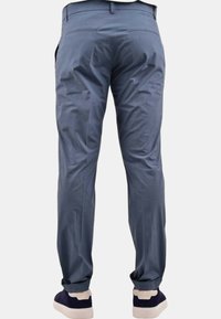 Pantaloni blu chiaro con una texture liscia, dotati di due tasche posteriori, design a gamba dritta e orli arrotolati sopra sneakers blu navy.