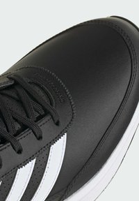 Sorte lærersneakers med tre hvite striper. Har svarte lisser og teksturerte detaljer. Rund tå og hvit såle.