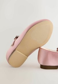 Ružová saténová topánka s nízkym podpätkom a srdcovou gumenou podrážkou, vybavená dekoratívnym remienkom a malou prackou.