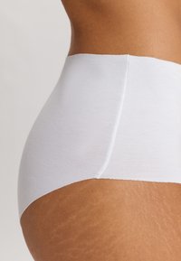 Bílé vysoké kalhotky s hladkým materiálem, bezešvým designem a širokým pasem, zobrazující detailní boční pohled.