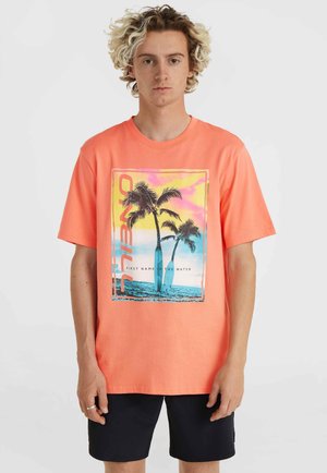 Camiseta de manga corta color coral con un gráfico de palmeras y playa. Acentos en azul claro y amarillo en el diseño; hecha de algodón.