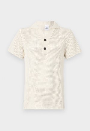Neulepolo paita vaaleassa valkoisessa, jossa on tekstuuripinta, lyhyet hihat ja kolme nappia sisältävä napitus, jossa on kontrastina mustat napit.
