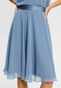 Kaunis A-linjan hame vaaleansinisestä sifongista, jossa on satiinivyötärö ja kerroksellinen helma, tarjoten pehmeän ja kevyen tekstuurin.