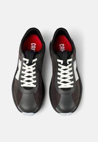 Sneaker neri e grigi con una finitura testurizzata, lacci bianchi, una soletta rossa e un accento bianco del logo sul lato. Design della punta arrotondata.