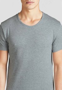 T-shirt in cotone grigio con scollatura rotonda e maniche corte, caratterizzato da una texture liscia e un design minimale.