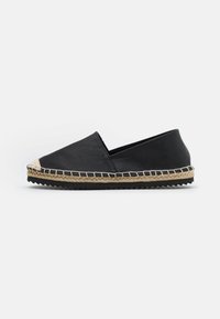 Černé espadrilky na slip-on s juty obtočenou podrážkou, bílým šitím a texturovanou gumovou podrážkou, zobrazené v bočním profilu na bílém pozadí.