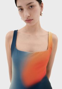 Plavky s čtvercovým výstřihem, které mají gradient modrých a oranžových odstínů. Hladký materiál s širokými ramínky a přiléhavým střihem.