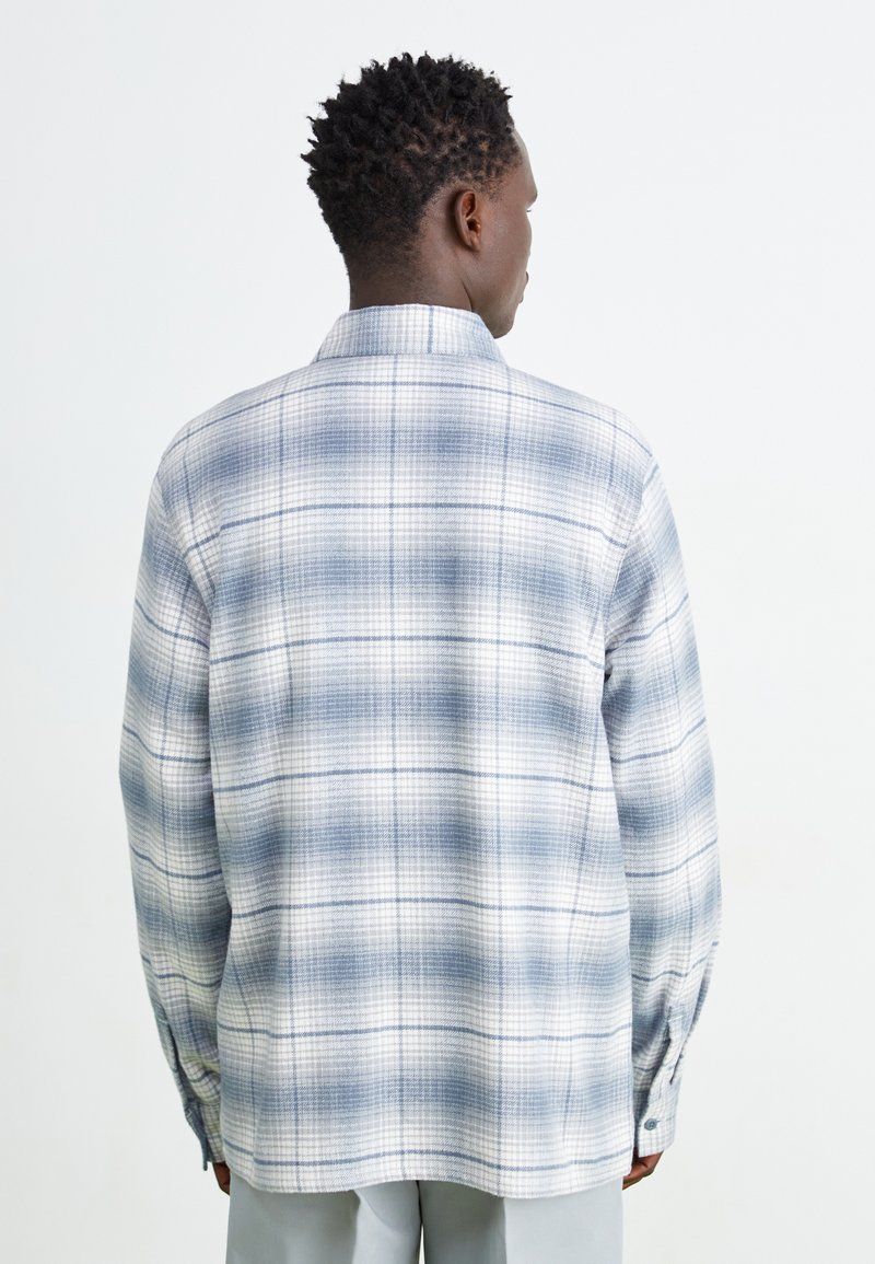 Camicia con bottoni in un tessuto leggero, caratterizzata da un motivo a quadri blu e bianchi, colletto e maniche lunghe con polsini abbottonati.