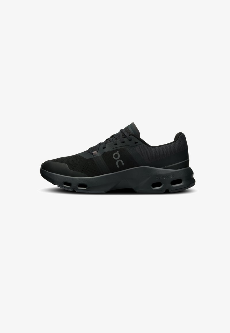 Chaussure de sport noire avec un dessus texturé, des panneaux en mesh et une semelle rembourrée dotée de perforations pour la respirabilité et l'absorption des chocs.