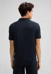 Marineblaue Poloshirt, kurze Ärmel, klassischer Kragen, glatte Textur und gerader Schnitt. Keine sichtbaren Logos oder Muster.