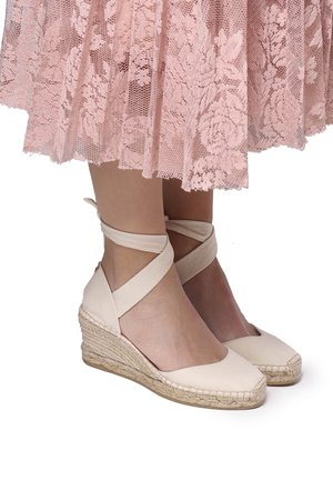 Beige espadrille sleehakken van canvas, met kruislings enkelbandjes en een geweven jute zool, met een gladde textuur en een rond teenontwerp.