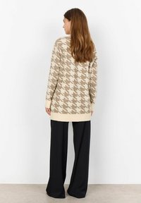 Beige knit sweater with houndstooth pattern, ribbed cuffs, and hem, paired with black wide-leg pants. Soft texture, casual fit.