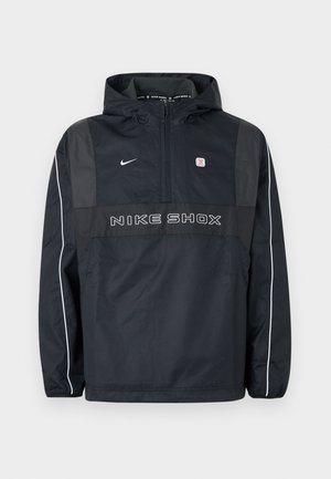 Črno pulover jakna Nike Shox s kapuco in polovičnim zadrgo, belim trakom na rokavih, logotipom Nike in napisom »NIKE SHOX« na sprednji strani.