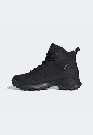 Scarpa da trekking nera alta con suola robusta, allacciatura anteriore e supporto imbottito per la caviglia su sfondo chiaro uniforme.