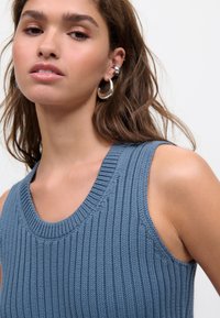 Camiseta de punto azul con cuello amplio y escote redondo, sin mangas. Presenta un acabado texturizado y una silueta ajustada.