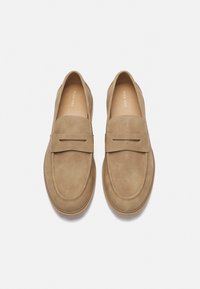 Barna nubuk slip-on cipők lekerekített orral, varrott részletekkel és minimalista kivágással az elülső pánton. Simát tapintás.