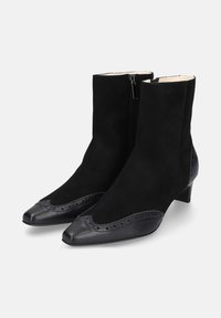 Zwarte enkellaarzen met een bovenkant van suede en een leren neuskap, decoratieve perforaties en een lage hak. Zijrits voor gemakkelijk aan- en uittrekken.