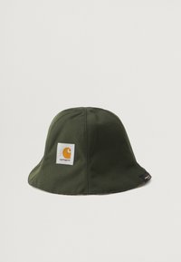 Chapéu de palha verde feito de tecido durável, apresentando um patch quadrado branco com um logótipo laranja. Forma arredondada com uma aba larga e flexível.