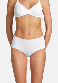 Weißer BH mit verstellbaren Trägern und einem glatten, nahtlosen Design; kombiniert mit hochgeschnittenen weißen Pants aus weichem Stoff.