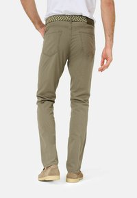 Khaki broek met een slim fit, voorzien van achterzakken, een gestructureerde stof en een geborduurde riem in groen en wit, gedragen met lichtbruine schoenen.