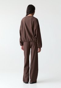 Brown, lightweight, long-sleeve top with elastic waistband paired with matching loose-fit pants. Smooth texture and relaxed silhouette.