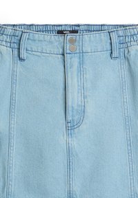Falda de mezclilla azul claro con cintura elástica, dos botones plateados y detalles de bolsillo cosidos. Tejido texturizado con un acabado suave.
