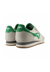 Sneaker con una toma in suede verde, pelle beige e una suola in gomma grigia texturizzata. Logo del canguro ben visibile sul tallone.