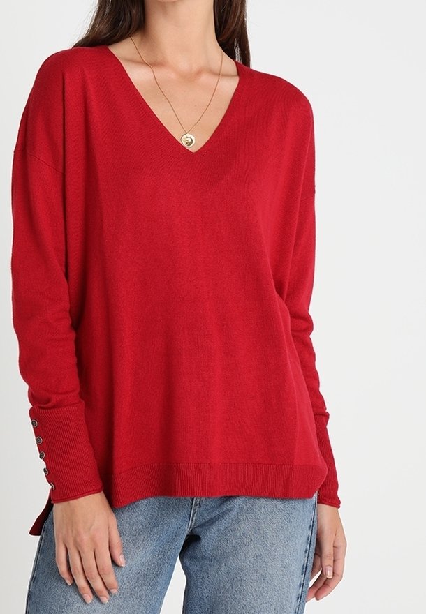 Rød v-hals sweater med lange ærmer og sideslids. Har knapdetaljer på ærmekanterne. Lavet af blødt, let materiale.