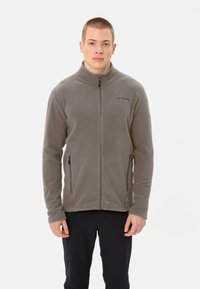 Giacca in fleece grigia con colletto alto, apertura con zip sul davanti e due tasche laterali. Presenta un piccolo logo sul petto e un tessuto morbido e testurizzato.