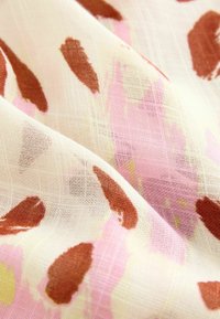 Doorzichtig stof met een zachte textuur, met een abstract patroon in roze, bruin en lichtgele tinten tegen een crème achtergrond.