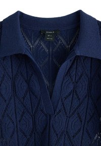 Polo shirt tricot di colore blu navy con un motivo a diamante testurizzato, scollo a V e colletto; etichetta indica la taglia S, prodotto in Turchia.