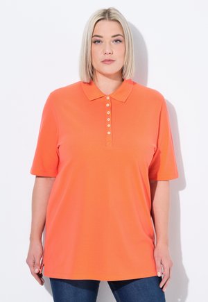 Oranje polo met korte mouwen, een knoopsluiting met crèmekleurige knopen, en een losse pasvorm, gecombineerd met donkerblauwe jeans.