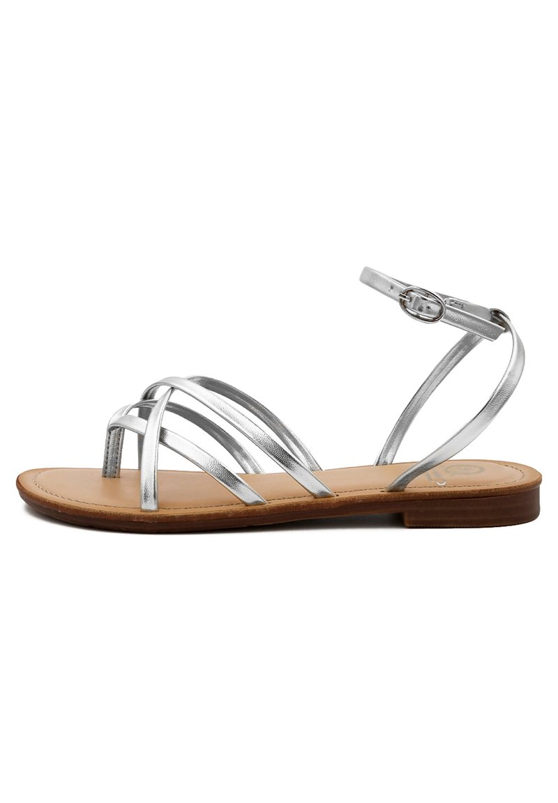 Sandalo strappy argento metallico con suola piatta color tortora, caratterizzato da multiple cinture incrociate e una fibbia regolabile alla caviglia.