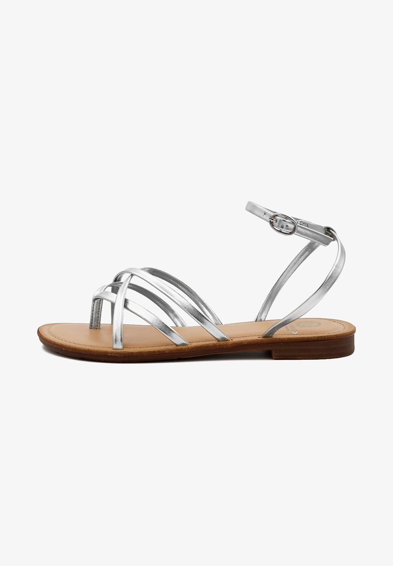 Sandalo strappy argento metallico con suola piatta color tortora, caratterizzato da multiple cinture incrociate e una fibbia regolabile alla caviglia.