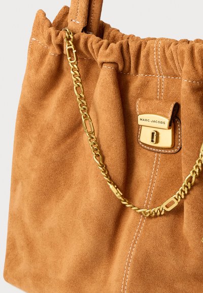 Wildleder-Shopper in Hellbraun mit gerafftem oberen Teil. Verfügt über einen goldenen Kettengurt und einen goldenen Verschluss mit "Marc Jacobs"-Branding. Weiße Steppnähtedetails.