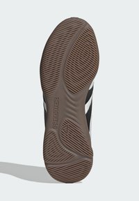 Zool van een zwart-witte Adidas Predator schoen met een getextureerde bruine rubberen loopvlak voor grip en het Adidas-logo nabij de hiel.