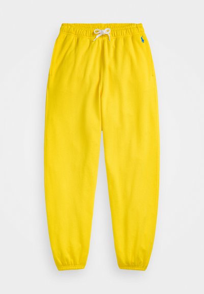 Žlté jogger nohavice vyrobené z mäkkej látky, s elastickým pásom so šnúrkou a elastickými manžetami. Obsahuje malý modrý logo detail.