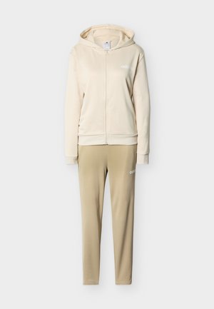 Sudadera con capucha beige con cremallera y pantalones ajustados a juego en beige, ambos con pequeños logotipos blancos de Adidas en el pecho y el muslo.