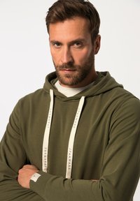 Olijfgroene hoodie met een voorste kangoeroe-pocket, crèmekleurige koordjes met tekst en ribgebreide manchetten. Zachte, gladde stoftextuur.
