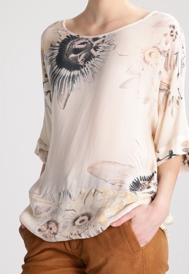 Blouse légère en crème avec un motif floral dans des couleurs douces, décolleté arrondi et manches 3/4. Coupe légèrement décontractée avec un ourlet arrondi.