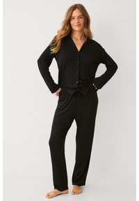 Ensemble de pyjama noir à manches longues en tissu doux ; chemise avec boutons et poche, pantalon à taille élastique ; design à longueur complète, coupe décontractée.