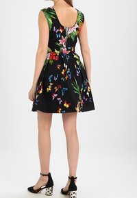 Sukienka w kwiatowy wzór na czarnym tle, bez rękawów, z rozszerzanym dołem. Udekorowana motylami w różnych kolorach.
