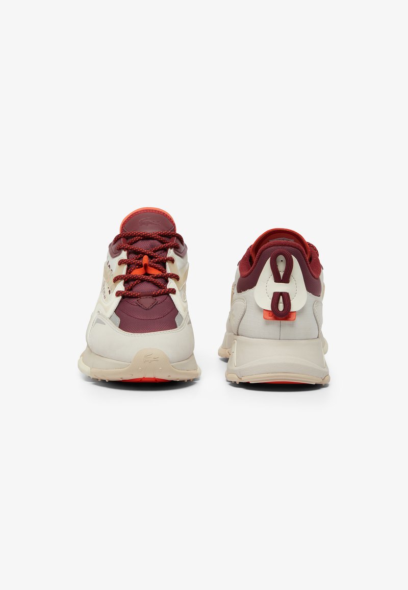 Sneakers con parte superiore color bordeaux e crema, inserti in rete testurizzata, accenti arancioni e una suola ammortizzata con un distintivo dettaglio a loop sul retro.