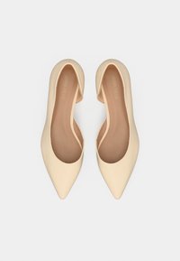 Μπεζ γόβες μυτερές, με υφή που μοιάζει με μαλακό δέρμα και πλευρές με χαμηλή κοπή. Διαθέτουν εσωτερική σόλα σε ανοιχτό καφέ χρώμα με διακριτική σήμανση.