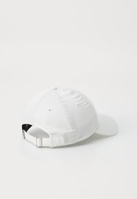 Cappellino da baseball bianco con visiera curvata, texture in tessuto, cinturino posteriore regolabile e fori di ventilazione sui pannelli laterali.