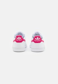 Vita lädersneakers med en rosa hälflik, med "Stan Smith"-logotypen och trefoil-design. Rundad tå och platt gummisula.